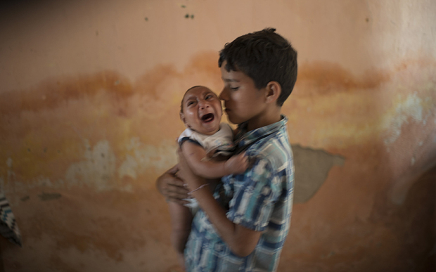 In this Dec. 23, 2015 photo, 10-year-old Elison nurses his 2-month-old brother Jose Wesley at their house in Poco Fundo, Pernambuco state, Brazil. Suspicion of the link between microcephaly and the Zika virus arose after officials recorded 17 cases of central nervous system malformations among fetuses and newborns after a Zika outbreak began last year in French Polynesia, according to the European Center for Disease Prevention and Control. (AP Photo/Felipe Dana)